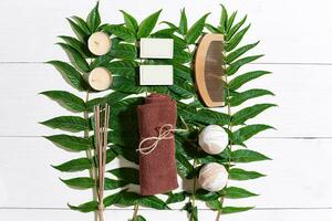 Spa set with towel and soap on white wooden background with green leaves photo