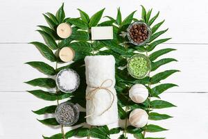 Spa set with towel and soap on white wooden background with green leaves photo