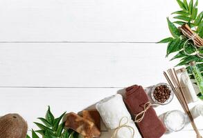 Spa set with towel and soap on white wooden background with green leaves photo