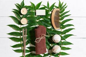 Spa set with towel and soap on white wooden background with green leaves photo