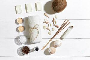 Spa set with sea salt, essential oil, soap and towel decorated with seashells on white wooden background photo