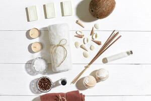 Spa set with sea salt, essential oil, soap and towel decorated with seashells on white wooden background photo