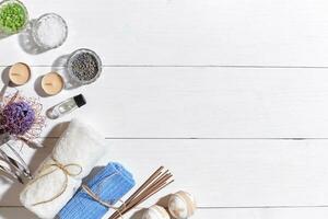 Spa set with sea salt, essential oil, soap and towel decorated with dry flower on white wooden background photo