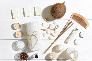 Spa set with sea salt, essential oil, soap and towel decorated with seashells on white wooden background photo