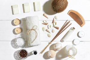 Spa set with sea salt, essential oil, soap and towel decorated with seashells on white wooden background photo