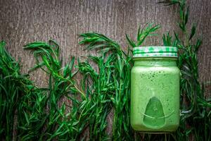 Glass of spinach juice on wooden background photo