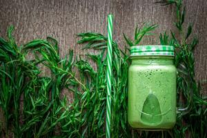 Glass of spinach juice on wooden background photo