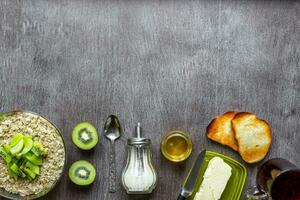 Oatmeal with kiwi, toast with butter and honey on a wooden table. The concept of a healthy breakfast photo