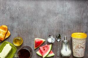 Oatmeal with watermelon, toast with butter and honey on a wooden table. The concept of a healthy breakfast photo