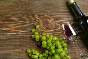 anteojos, botella de rojo vino y uva en un de madera mesa foto