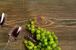 Glasses of wine and ripe grapes isolated on a wooden table photo