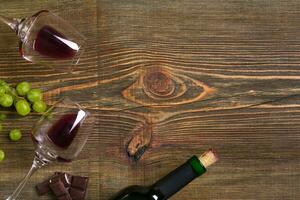 Two glasses, bottle of red wine and grape on a wooden table photo