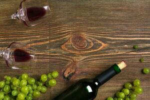 Red wine bottle, grape and glasses over wooden table. Top view with copy space photo