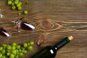 Red wine bottle, grape and glasses over wooden table. Top view with copy space photo