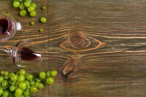 Glasses of wine and ripe grapes isolated on a wooden table photo