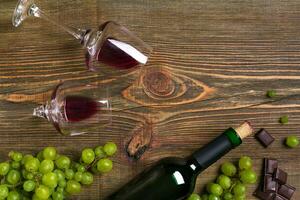 Two glasses, bottle of red wine and grape on a wooden table photo