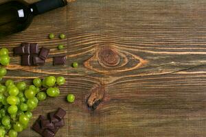Bottle of wine and ripe grapes on wooden background photo