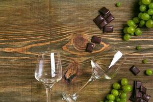 Two glasses of red wine, green grapes and chocolate, top view photo