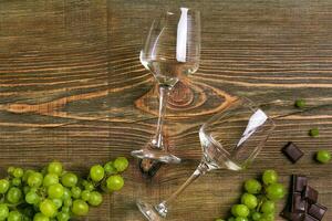 Glasses of wine and ripe grapes isolated on a wooden table photo