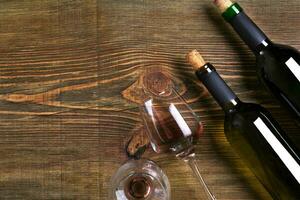 Bottles and two glasses of wine on wooden background from top view photo