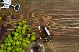 Two glasses of red wine, green grapes and chocolate, top view photo