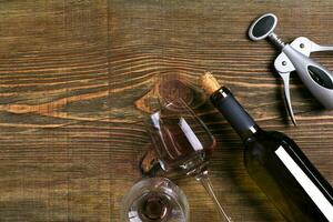 Bottle and two glasses of wine on wooden background from top view photo