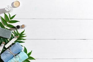 Spa set with towels and soap on white wooden background top view photo