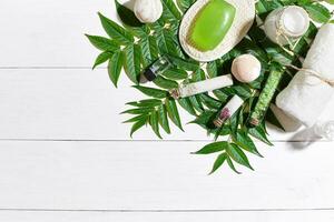 Spa set with towel and soap on white wooden background with green leaves photo