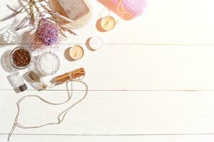 Spa set with sea salt, essential oil, soap and towel decorated with dry flower on white wooden background. Sun flare photo