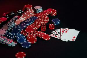 Casino chips and cards on black table surface. Gambling, fortune, game and entertainment concept - close up photo