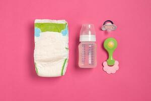 Baby care accessories and diapers on pink background. Top view photo