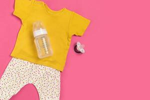 Baby clothes and accessories on pink background. Top view photo