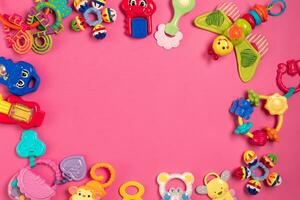 Children's rattle from plastic on a pink background. Top view photo