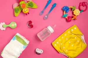 Baby care accessories and diapers on pink background. Top view photo