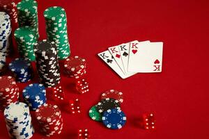 Casino gambling poker equipment and entertainment concept - close up of playing cards and chips at red background. Four of a Kind photo
