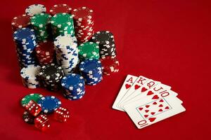 Casino gambling poker equipment and entertainment concept - close up of playing cards and chips at red background. Royal flush heart. photo