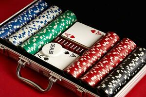 Poker set in metal suitcase. Risky entertainment of gambling. Top view on red background photo
