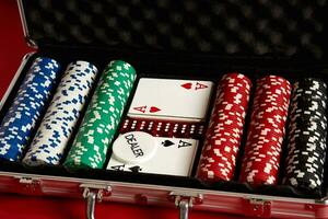 Poker set in metal suitcase. Risky entertainment of gambling. Top view on red background photo