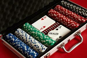 Poker set in metal suitcase. Risky entertainment of gambling. Top view on red background photo