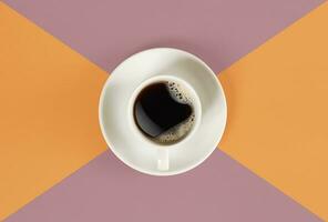 A cup of black coffee on orange and red background. View from above. photo