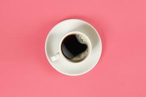 A cup of black coffee on pink background. View from above. photo