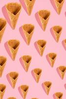 Sugar waffle cone for ice cream arranged in pattern on pink background. The image with copy space can be used as a background for the design of the confectionery menu photo