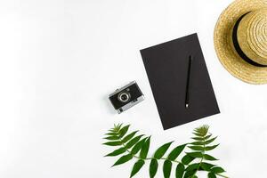 Straw hat with green leaves and old camera on white background, Summer background. Top view photo