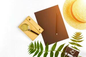 Straw hat with green leaves and old camera on white background, Summer background. Top view. Sun flare photo