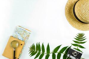 Straw hat with green leaves and old camera on white background, Summer background. Top view photo