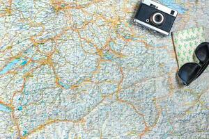 Map of roads with a vintage camera, passport, sunglasses. View from above. The concept of travel photo