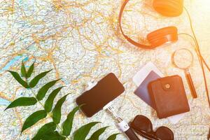 Accessories for travel. Passport, headphones, smart phone and travel map. Top view. Sun flare photo