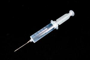 a syringe with a needle on a black surface photo