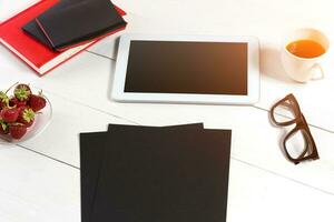 Stylish minimalistic workplace with tablet and notebook and glasses in flat lay style. White background. photo