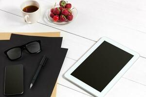 Tablet, blank sheet, glasses and coffee cup on office wooden table photo